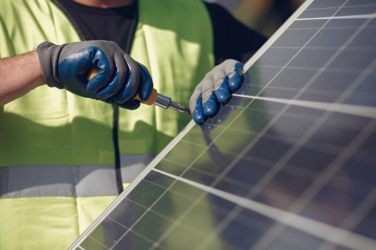 Ein Handwerker schraubt an einem Solarpanel.